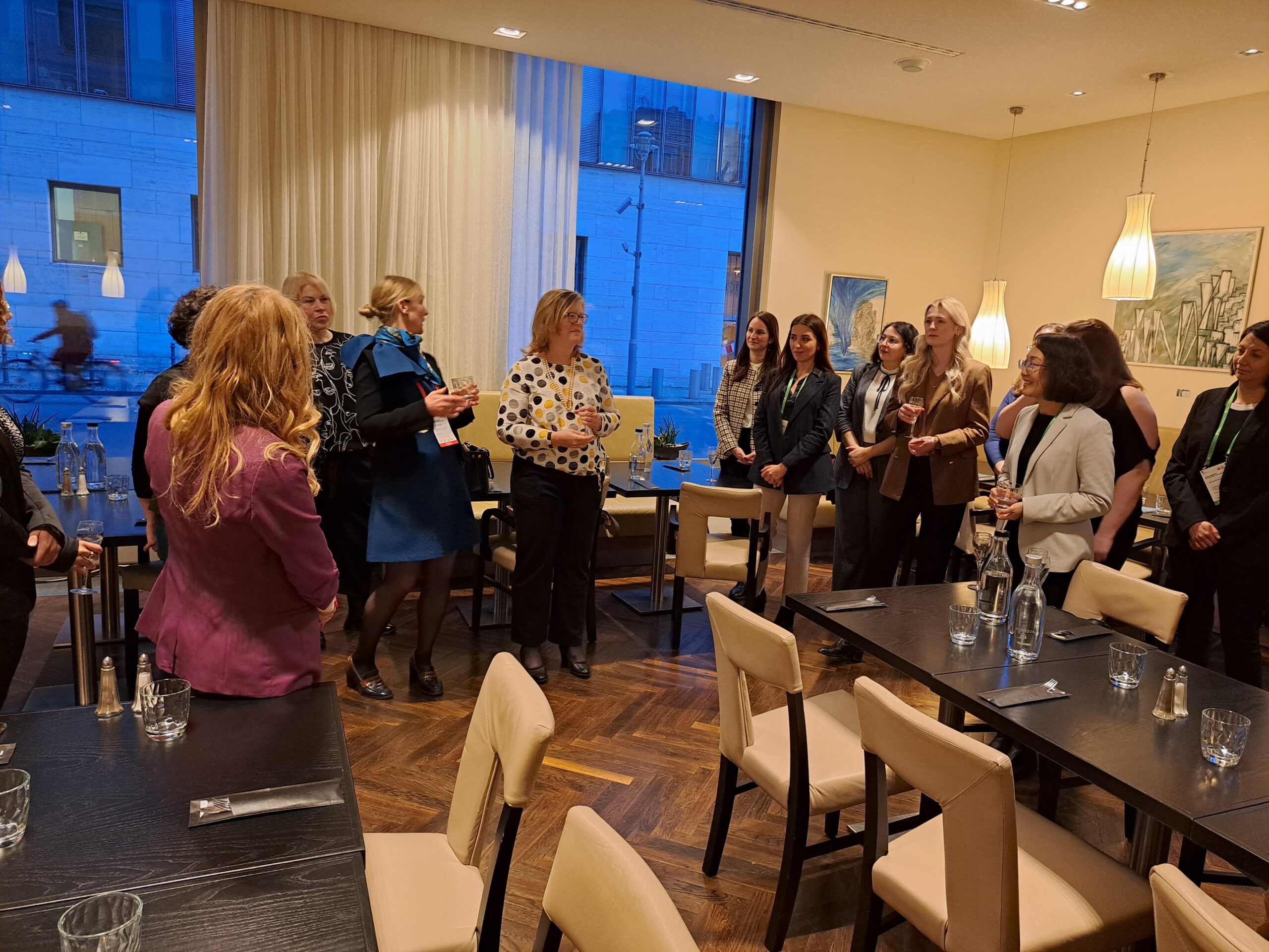 Women gathered around tables at a networking dinner, listening to the speaker