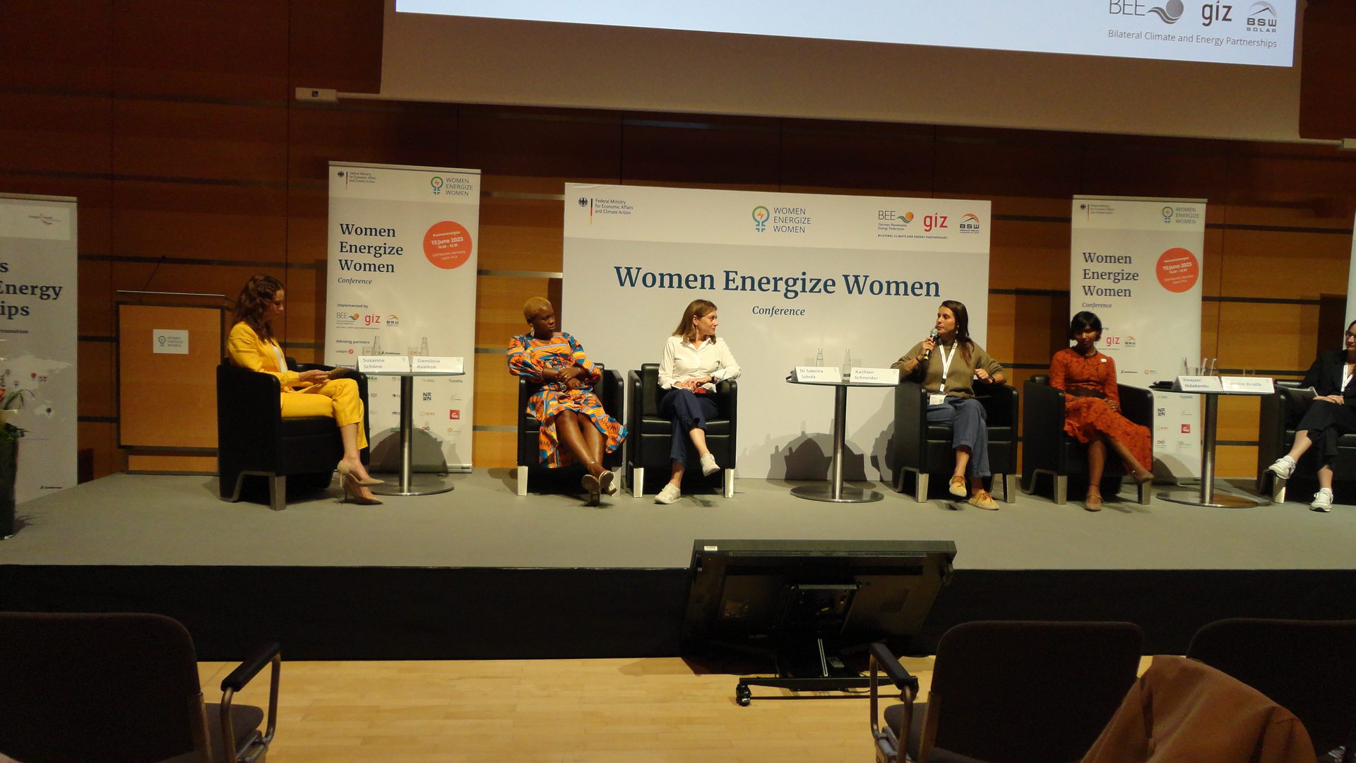 Women panelists on stage at a conference